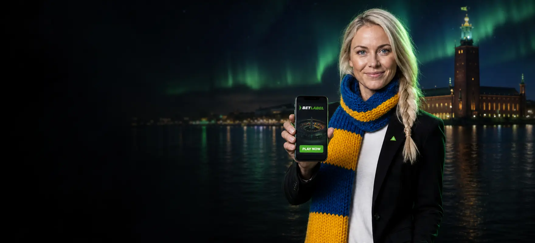 Woman with a platinum-blonde braid and a blue-and-yellow scarf showing a smartphone with the BetLabel app in front of Stockholm City Hall at night Woman with a platinum-blonde braid and a blue-and-yellow scarf showing a smartphone with the BetLabel app in front of Stockholm City Hall at night